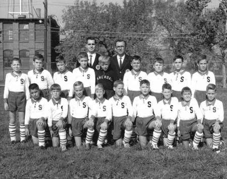 Vintage black-and-white team photo of young soccer players with their coaches