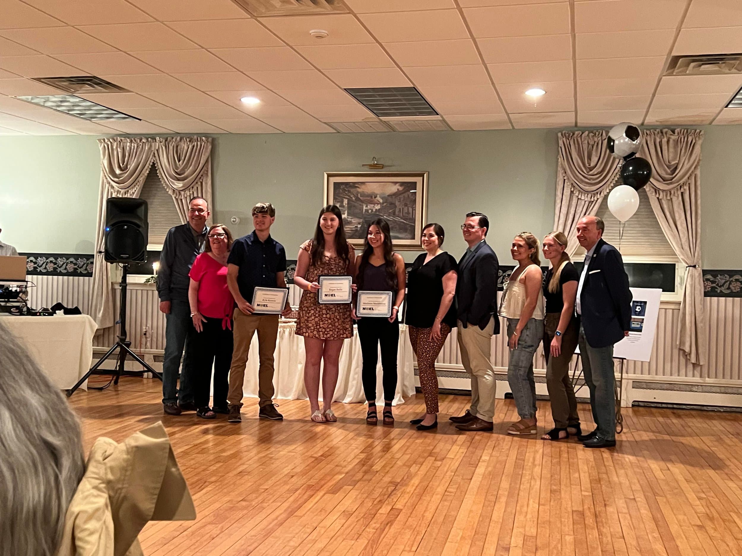 Noel Soccer Foundation scholarship recipients holding their award certificates with foundation members at the awards dinner